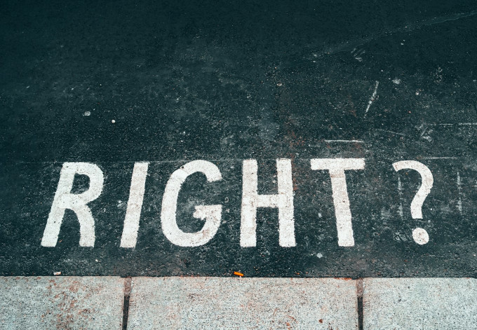 アスファルトの地面に「RIGHT?」の文字と右を指す矢印が描かれた、進むべき正しい進路や教育の選択肢を模索するイメージ